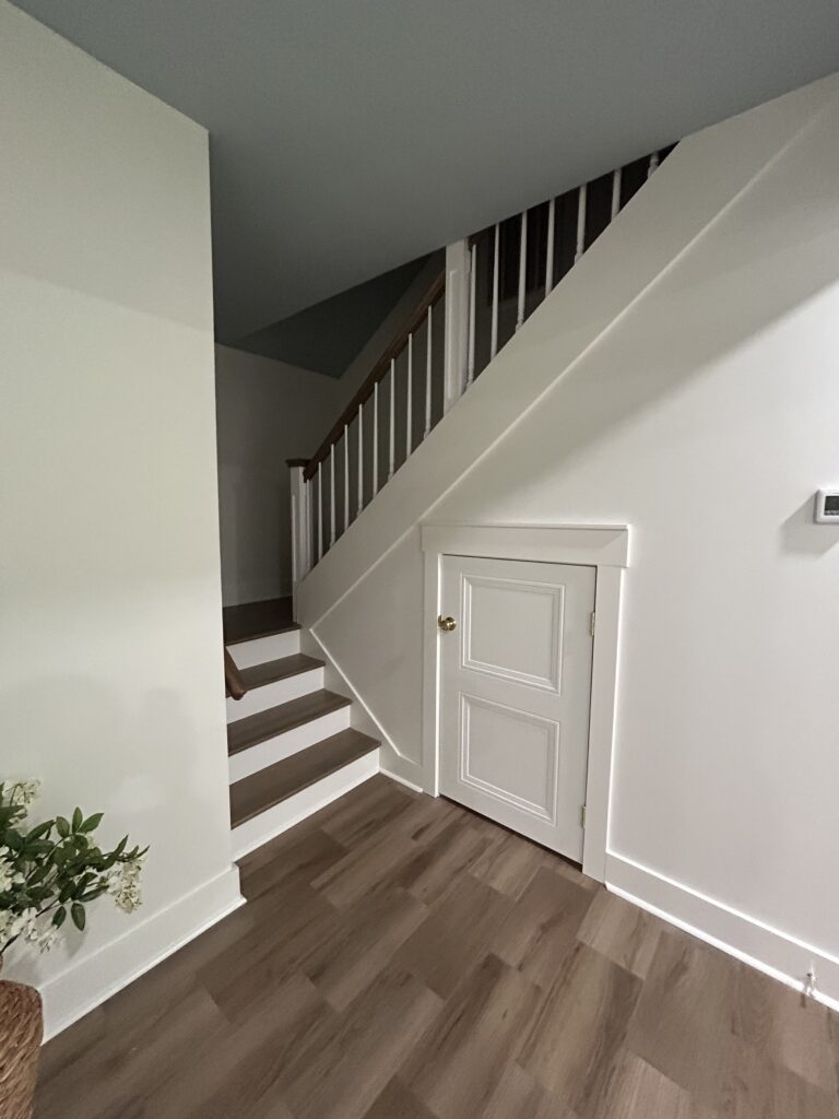 Wood staircase with white balusters, painted trim, and under-stair storage 